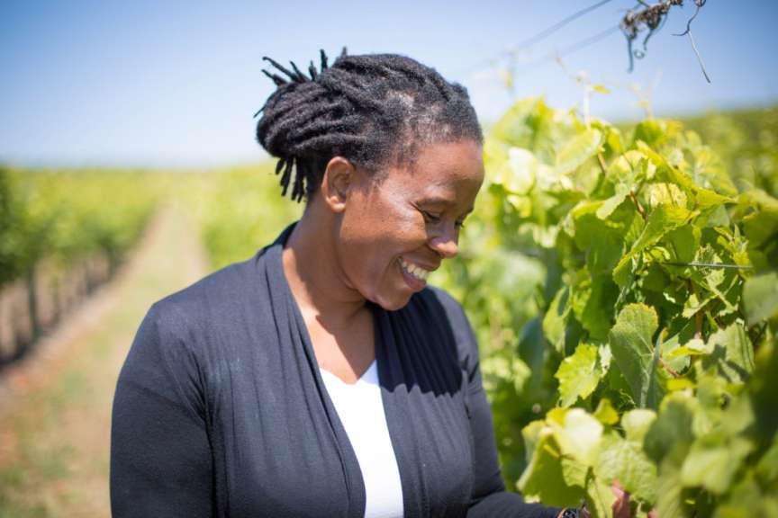Eine Frau mit dreadlocks lächelt und schaut auf einen Weinberg