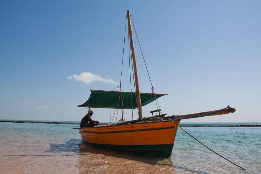 Ein Mann sitzt in einem gelb-grünen Boot am Strand