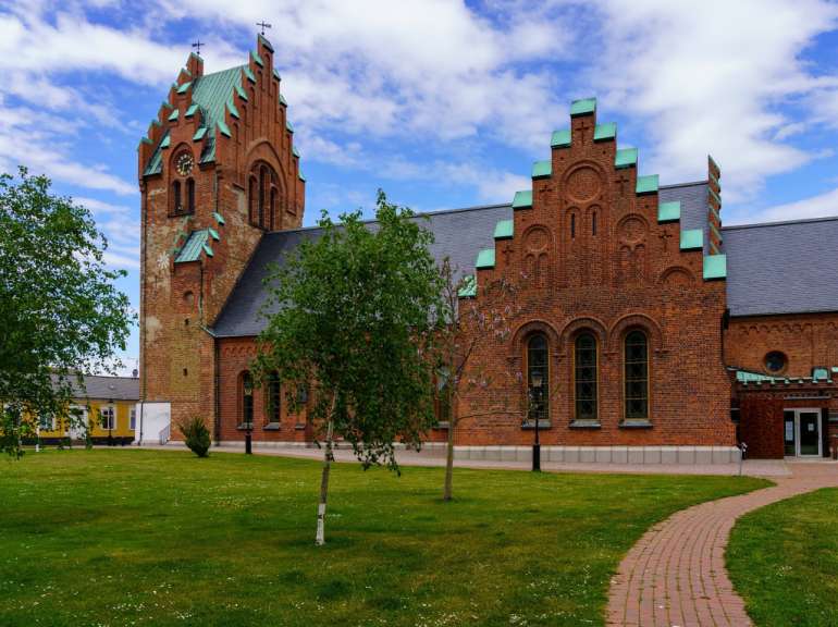 Eine rote Backsteinkirche mit einem grünen Dach