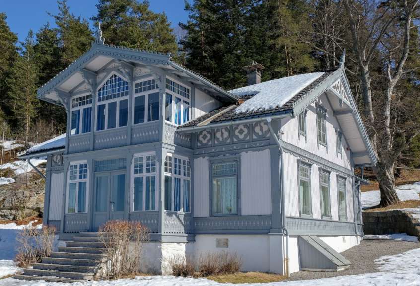 Ein weißes Haus mit blauen Fenstern und einem schneebedeckten Dach