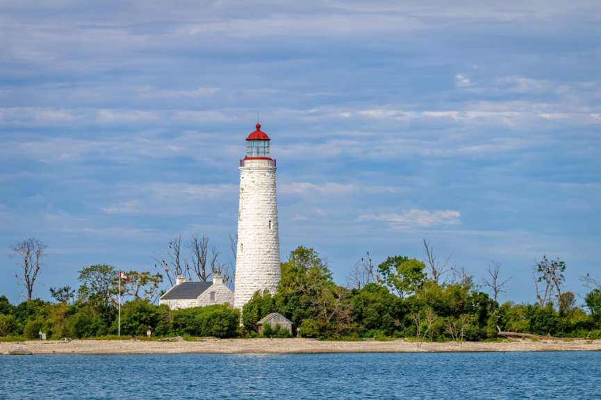 Ein weißer Leuchtturm mit einem roten Dach steht über einem See