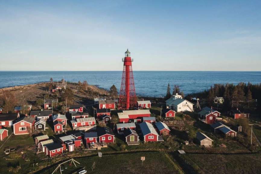 Ein kleines Dorf mit roten Häusern und einem Leuchtturm