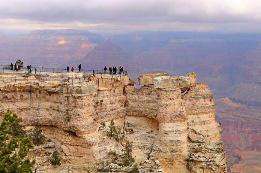 Eine Gruppe von Menschen steht auf einer Klippe mit Blick auf den Grand Canyon