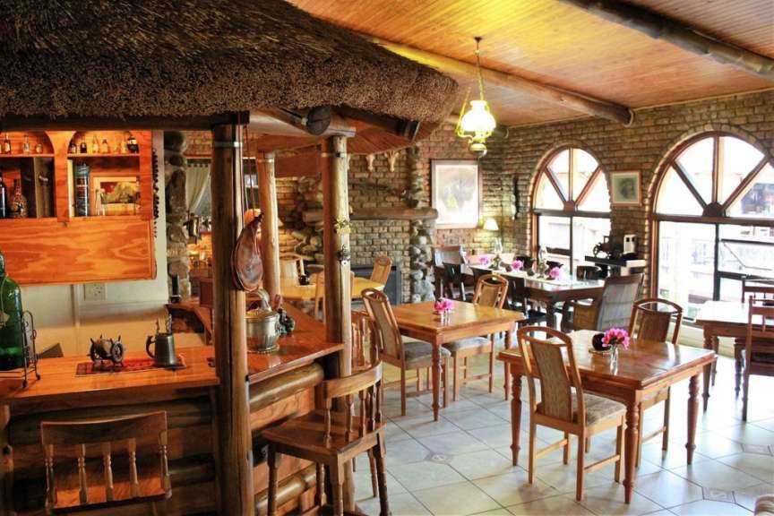 Ein Restaurant mit Tisch und Stühlen und einer Bar mit Strohdach