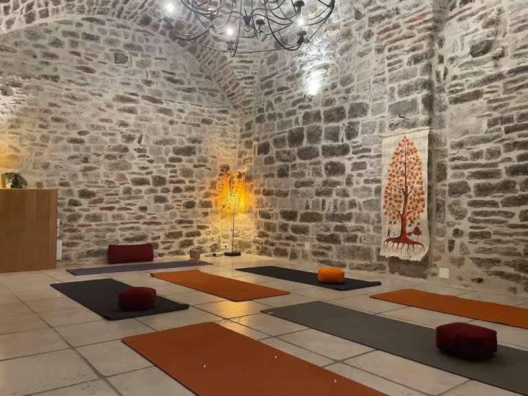 Ein Raum mit Yogamatten und Kissen und einem Gemälde eines Baumes an der Wand