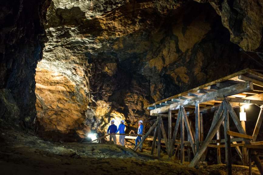 Zwei Männer stehen in einer Höhle neben einer Holzbrücke