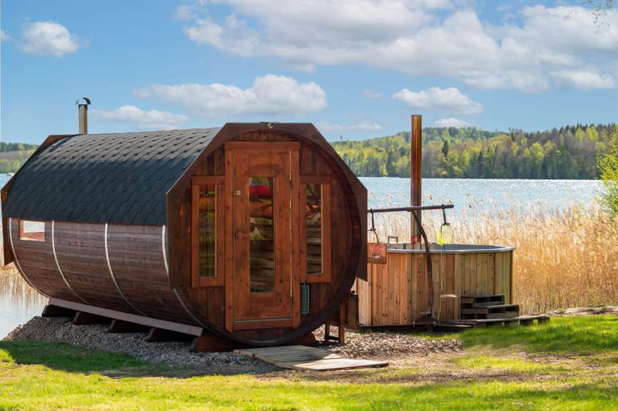 Eine Holzsauna mit einer Wanne neben einem See