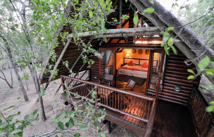 Ein kleines Holzhaus mit einem Balkon und einem Bett darauf