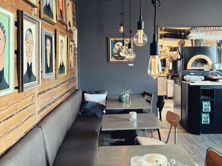 Eine Reihe von Tischen und Stühlen in einem Restaurant mit Bildern an der Wand