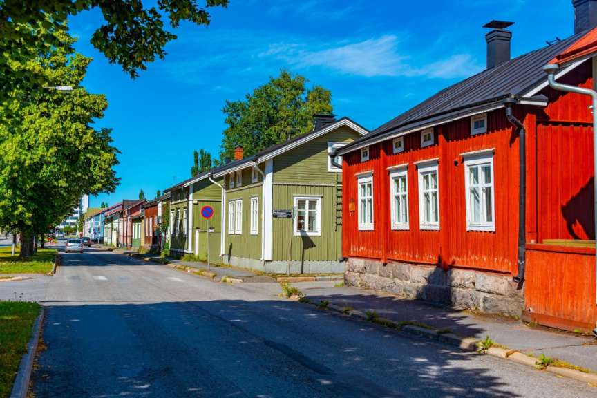 Eine Straße mit Holzhäusern, die an einem sonnigen Tag unter einem blauen Himmel gesäumt sind.