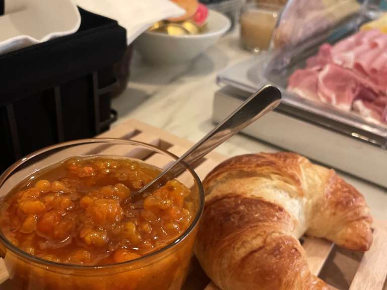 Ein Glas Marmelade neben einem Croissant mit einem Löffel