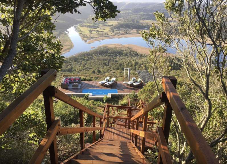 Eine Holztreppe führt hinunter zu einem Pool mit Blick auf einen Fluss