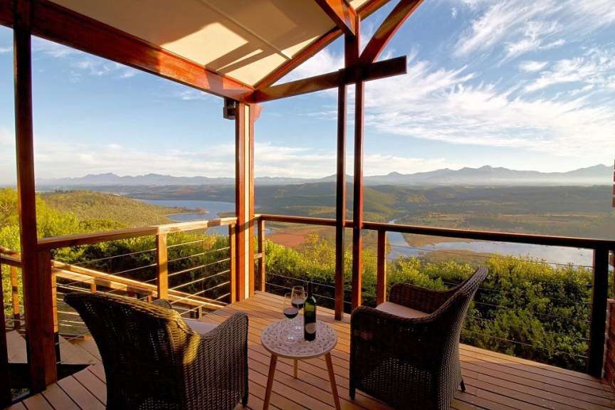 Ein Tisch mit zwei Gläsern Wein auf einem Deck mit Blick auf einen See