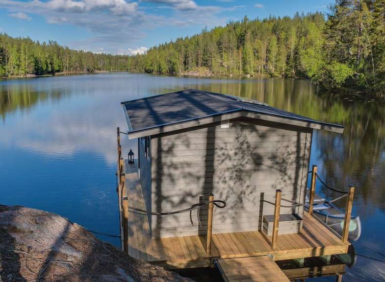 Ein kleines Haus sitzt auf einem Holzdock inmitten eines Sees