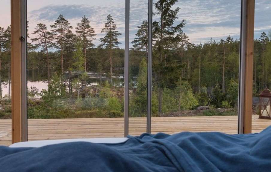Ein Bett mit einer blauen Decke und einem Fenster mit Blick auf einen See