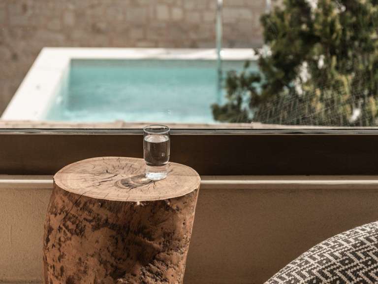 Ein Glas Wasser sitzt auf einem Holzblock vor einem Fenster