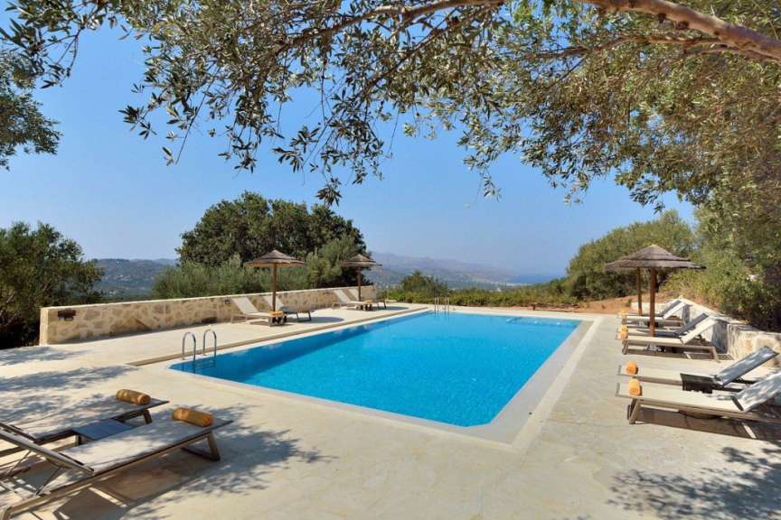 Liegestühle und Sonnenschirme umgeben einen großen Swimmingpool