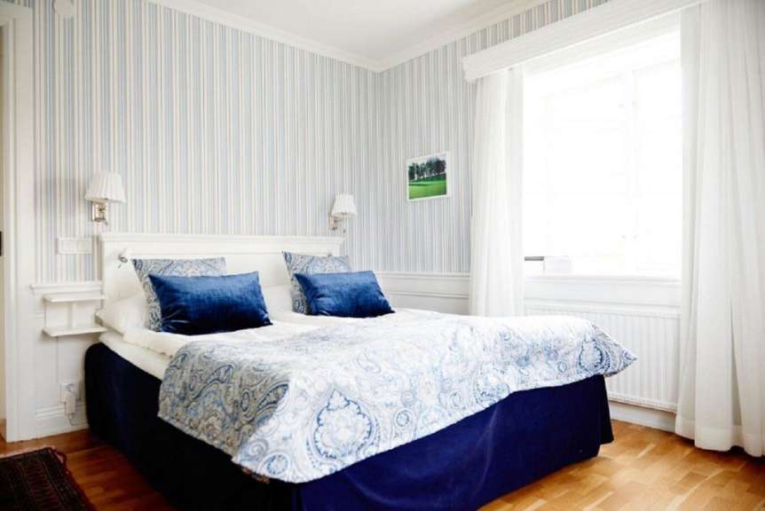 Ein Schlafzimmer mit blau-weiß gestreiften Wänden und einem Bett