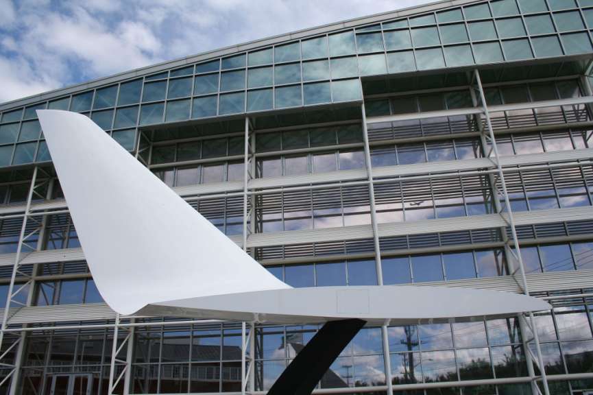 Ein großer weißer Flügel steht vor einem großen Glasgebäude