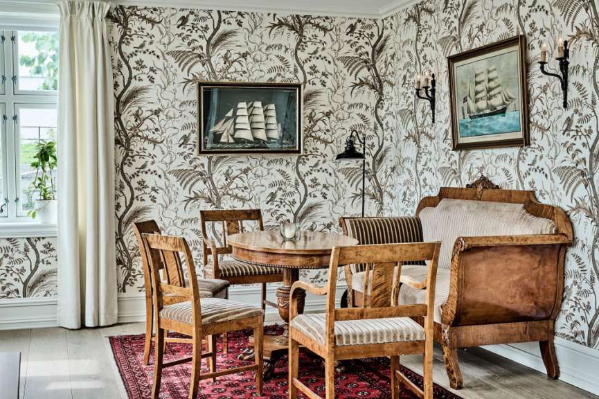 Ein Wohnzimmer mit einem Tisch und Stühlen und einem Gemälde eines Schiffes an der Wand