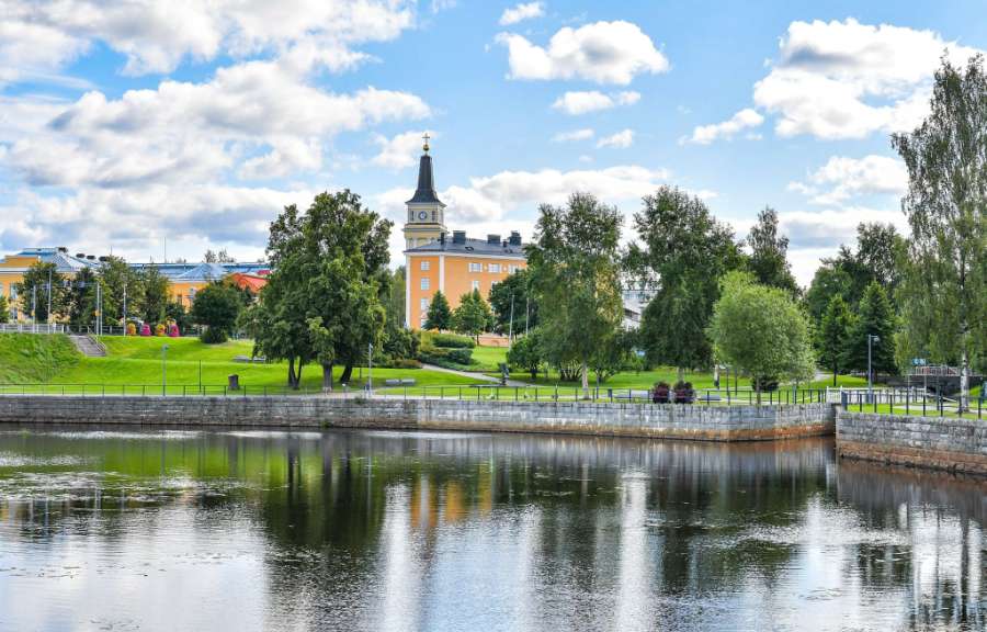 Ein Gebäude mit einem Uhrturm sitzt über einem Teich