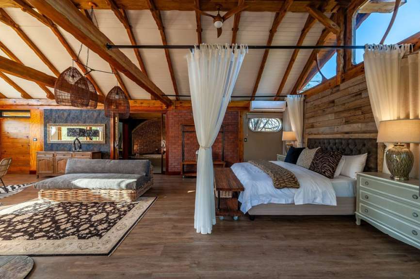 Eine luxuriöse Schlafzimmer-Suite mit einem Bett, einer Couch und rustikalen Holzakzenten.