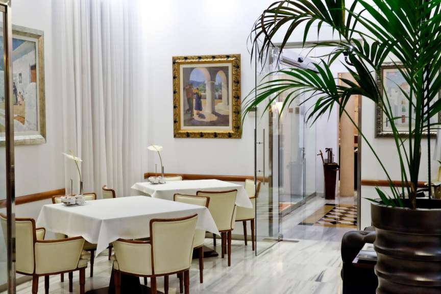 Ein Esszimmer mit Tischen und Stühlen und einem Gemälde an der Wand