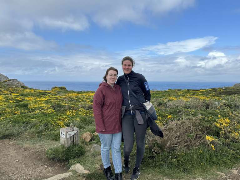 Zwei Frauen stehen nebeneinander in einem Feld mit gelben Blumen