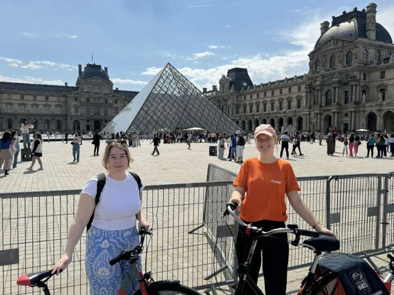 Zwei junge frauen stehen mit fahrrädern vor einer pyramide