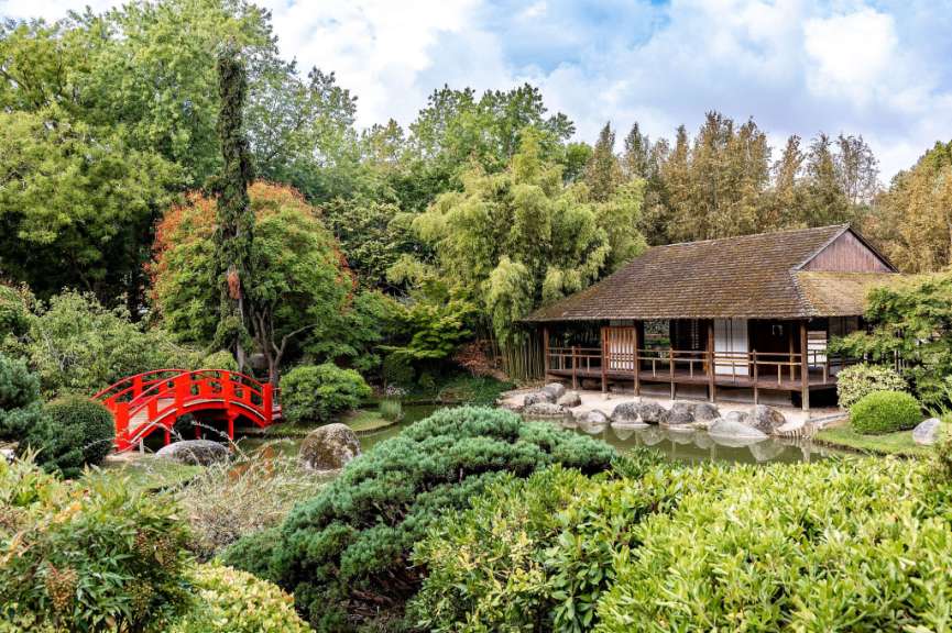 Ein japanischer Garten mit einem Haus und einer Brücke über einen Teich