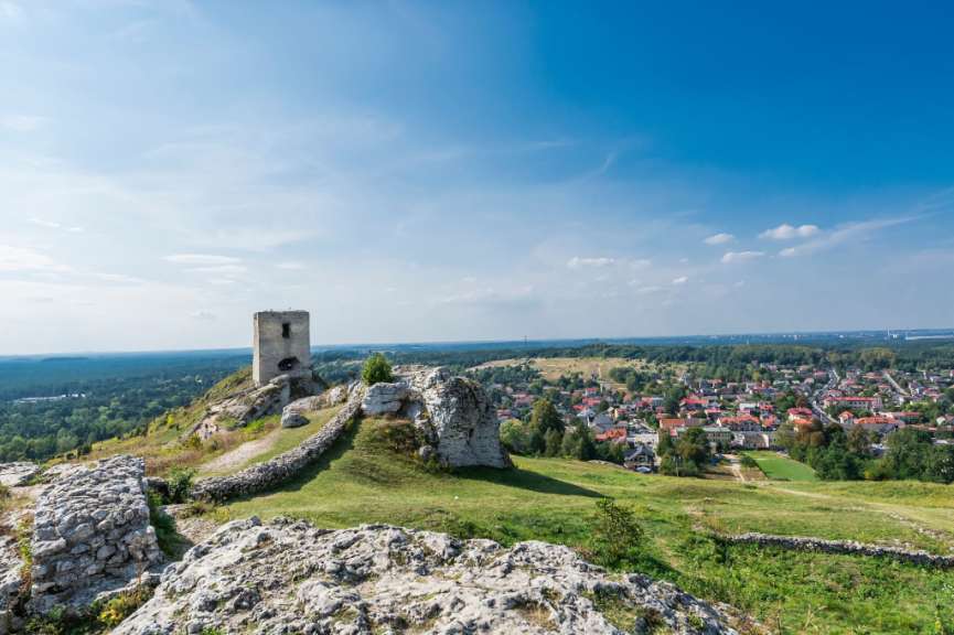 Eine Burgruine auf einem Hügel mit einer Stadt im Hintergrund