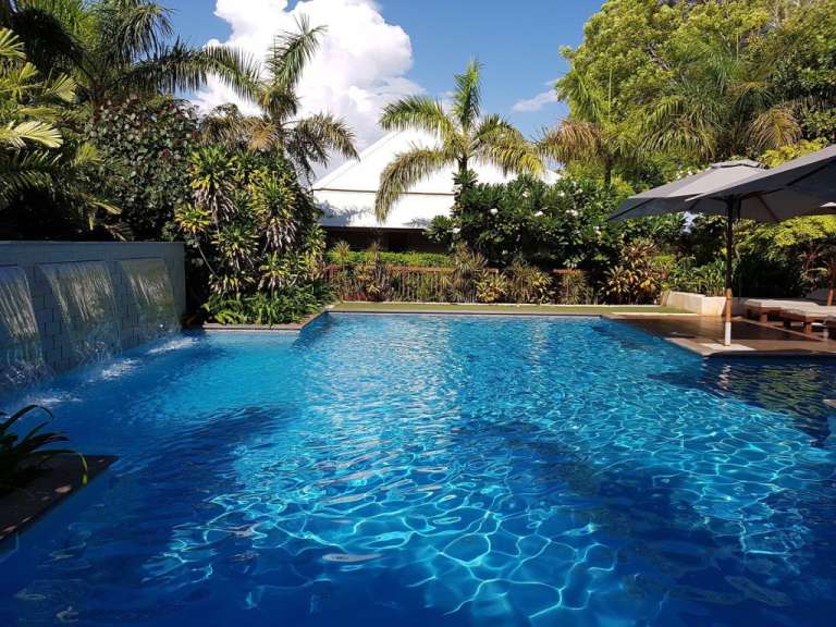 Ein großer blauer Pool mit einem Wasserfall im Hintergrund