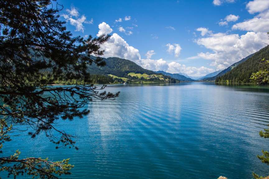 Ein See mit Bergen im Hintergrund und Bäumen im Vordergrund