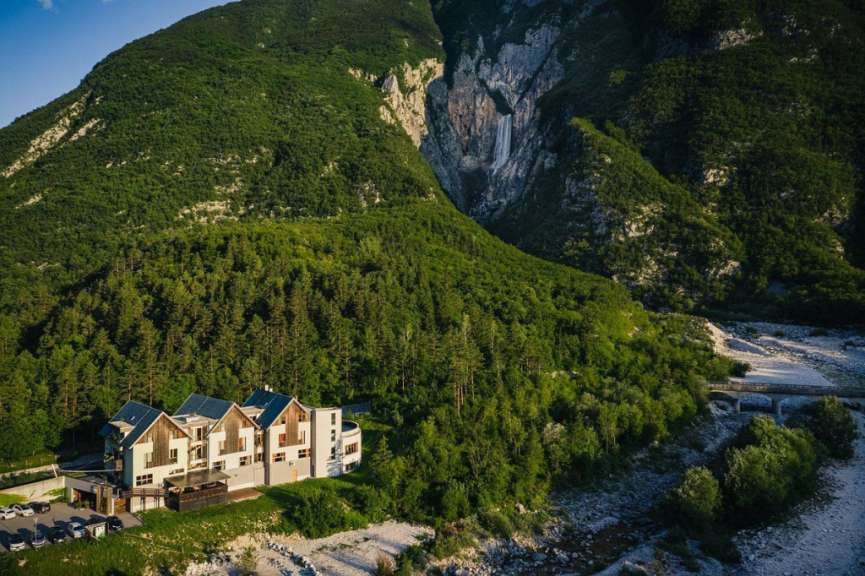 Ein Gebäude inmitten einer Bergkette mit einem Wasserfall dahinter
