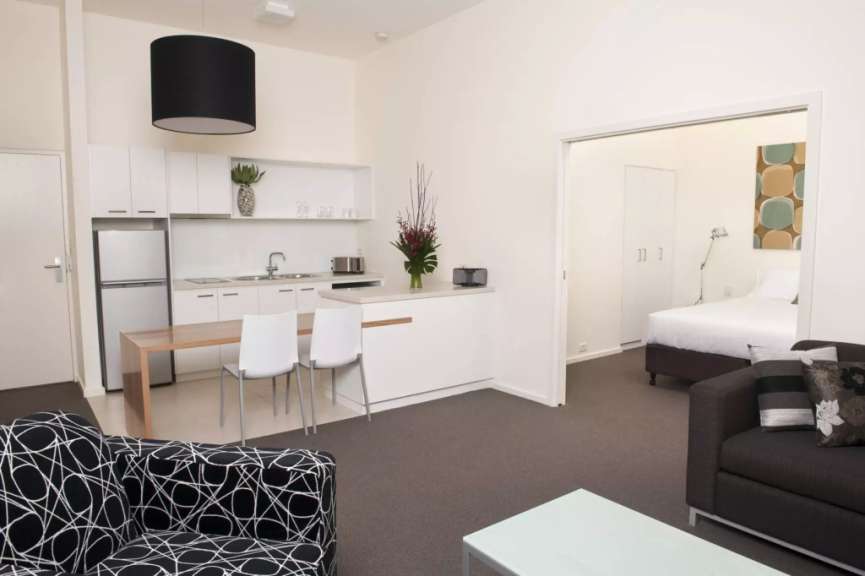 Ein Apartment mit offener Küche und Schlafzimmer ist von einem Wohnzimmer aus zu sehen.