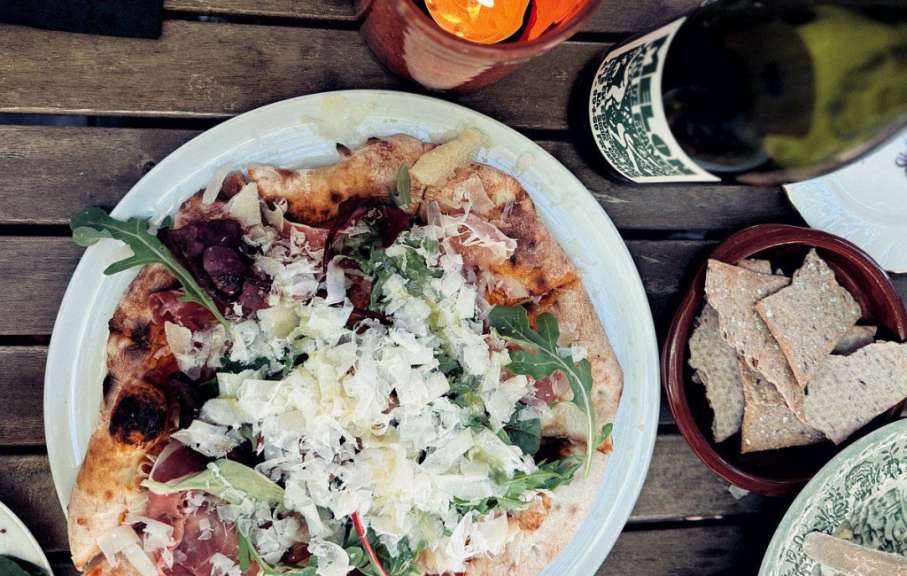 Ein weißer Teller mit einer Pizza und einer Flasche Wein darauf