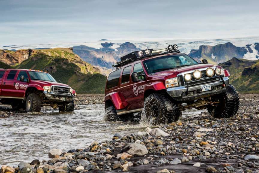 Ein roter ford truck fährt durch einen fluss