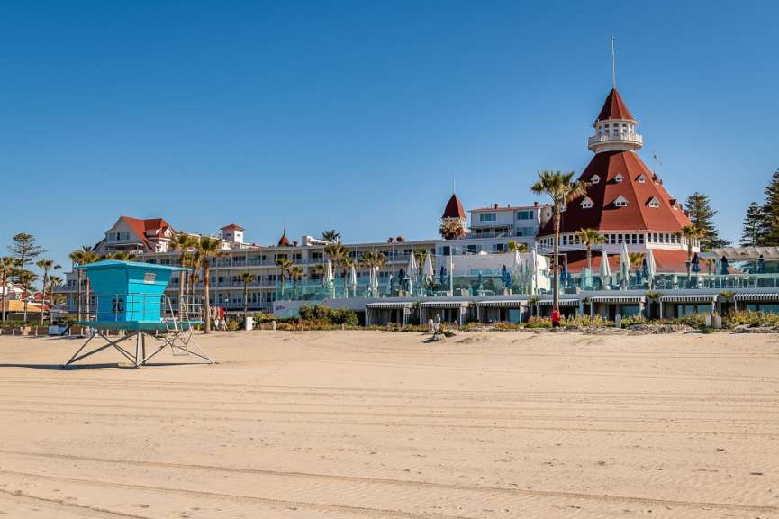 Ein blauer Rettungsturm steht am Strand vor einem großen Hotel
