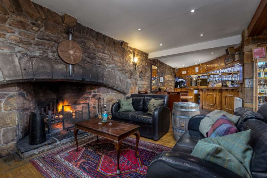 Eine gemütliche Lounge mit einem Kamin und einer Bar in einem rustikalen Gebäude.