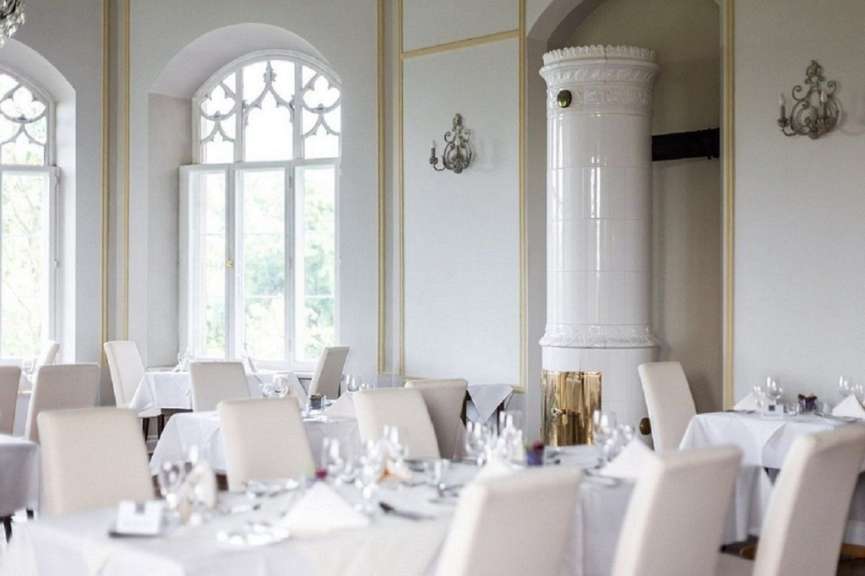 Ein Restaurant mit weißen Tischen und Stühlen und einem weißen Kamin