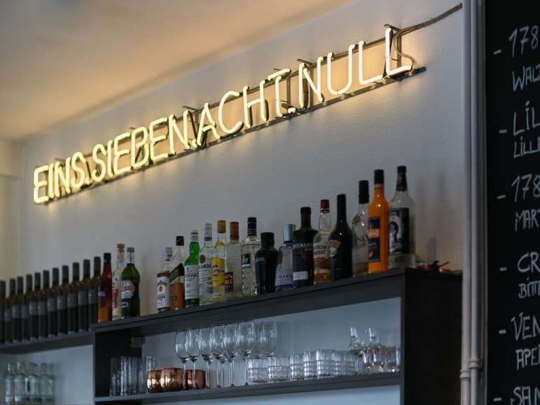 Eine Bar mit Flaschen und Gläsern und einem Leuchtschild darüber