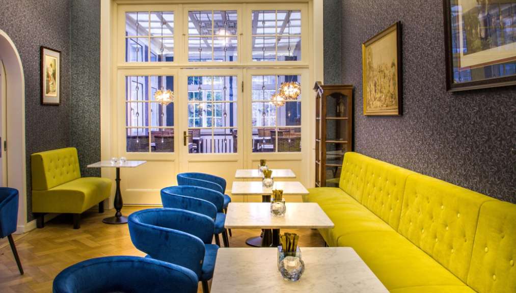 Ein Esszimmer mit blauen und gelben Stühlen und Tischen