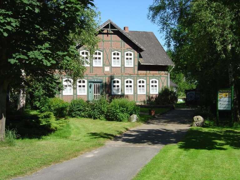 Eine Straße führt zu einem großen Backsteinhaus mit vielen Fenstern