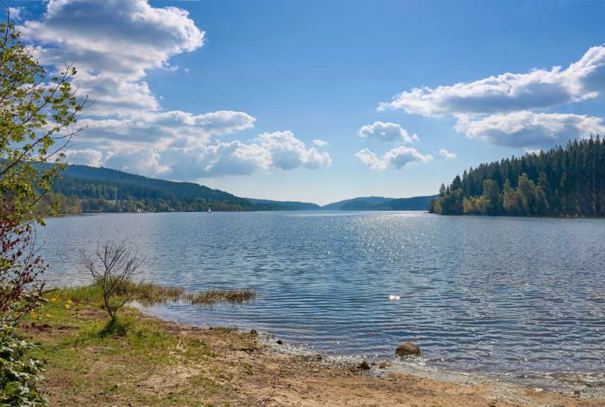 Ein See mit Bergen im Hintergrund und einem blauen Himmel mit Wolken