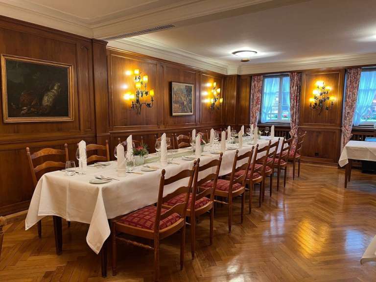 Ein langer Tisch mit weißen Tischdecken und Stühlen in einem Speisesaal