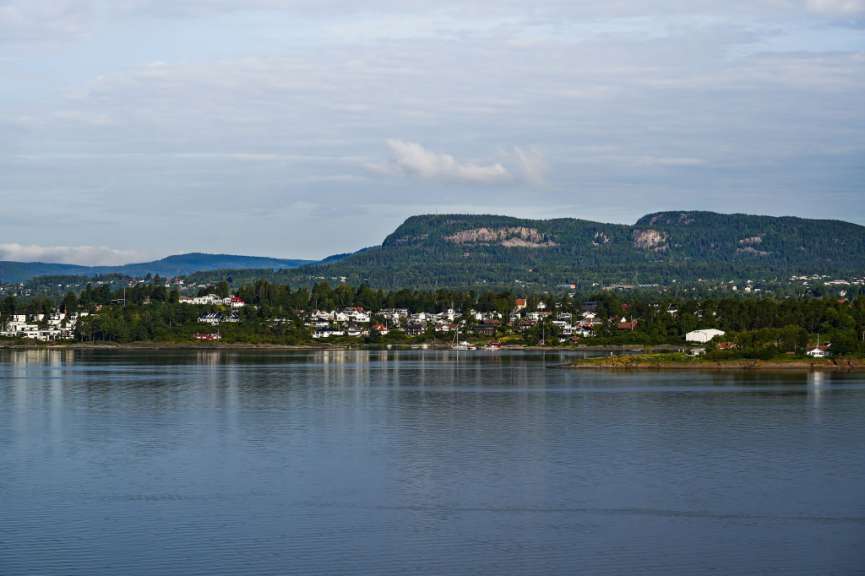 Eine Stadt liegt am Ufer eines Sees mit Bergen im Hintergrund