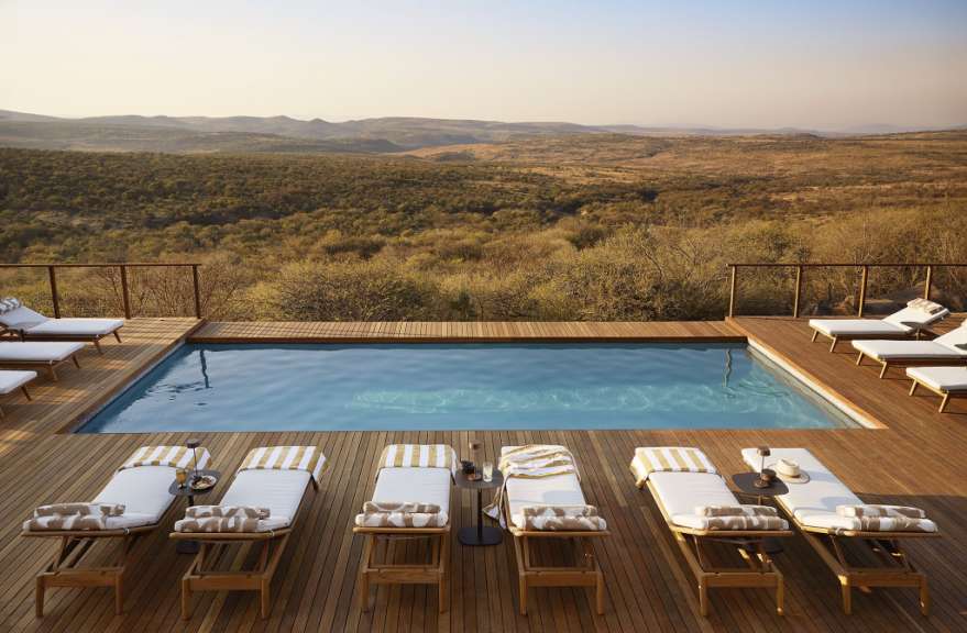 Liegestühle stehen neben einem Pool auf einem Holzdeck