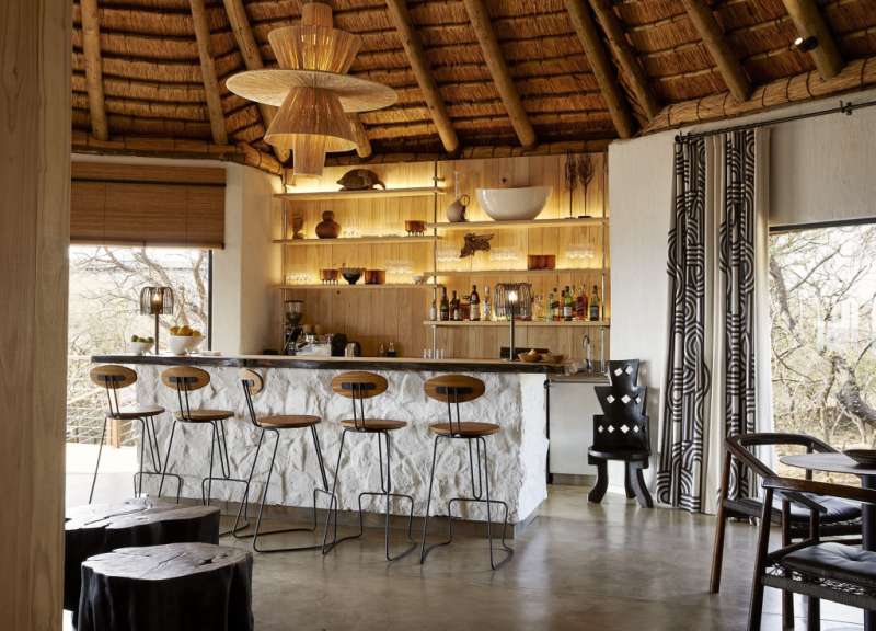 Eine Bar mit Holzstühlen und einem Strohdach