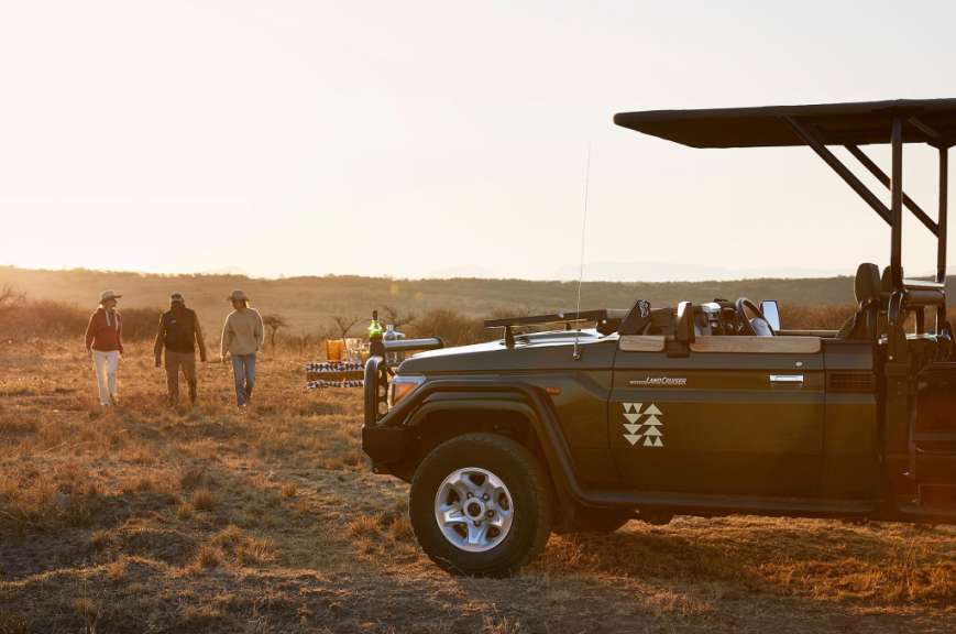 Eine Gruppe von Menschen geht neben einem schwarzen Landcruiser