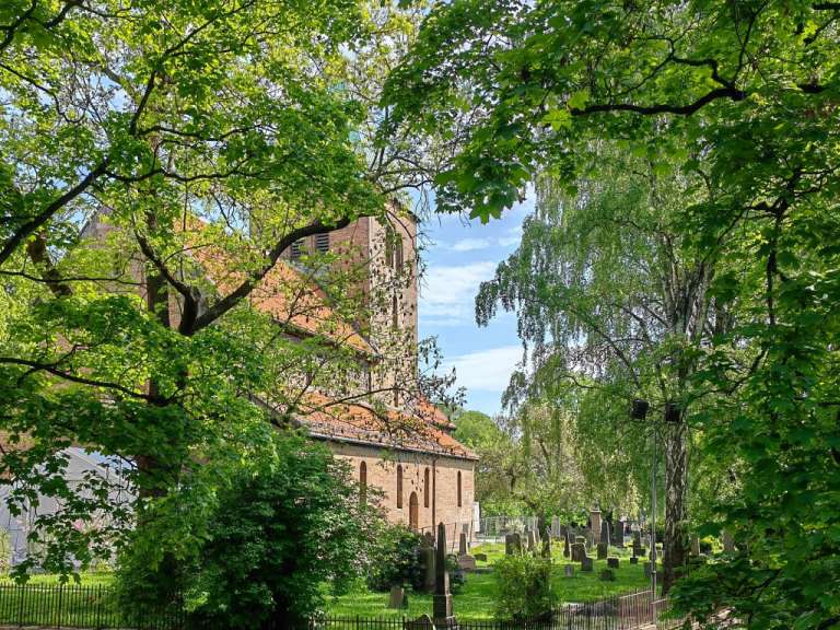 Eine Kirche umgeben von Bäumen und einem Friedhof